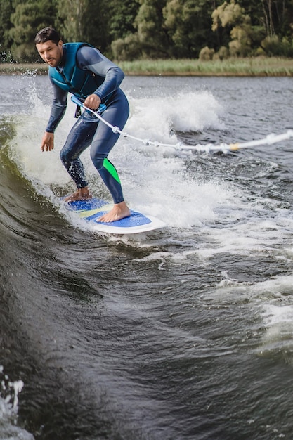 uomo su wakesurfing. saluta dalla barca.