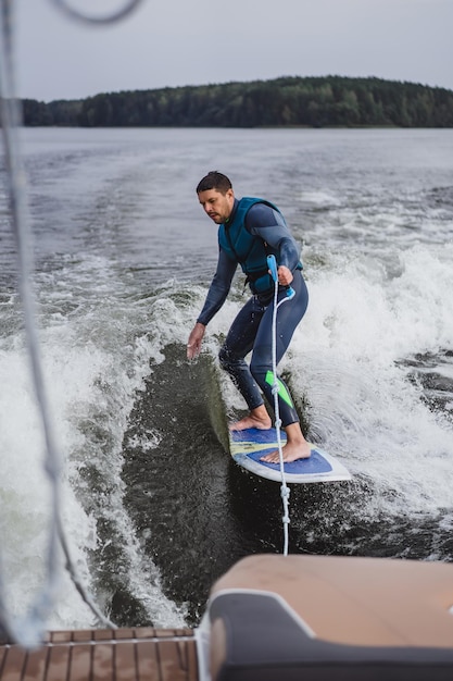 uomo su wakesurfing. saluta dalla barca.