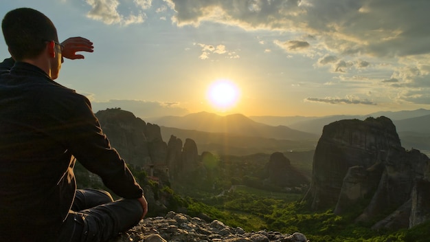 Uomo sulla cima della montagna al tramonto Grecia Meteora