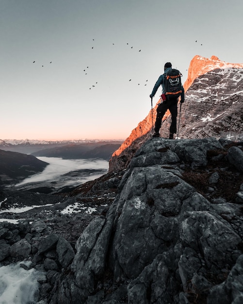 Uomo sulla roccia in montagna contro il cielo durante il tramonto