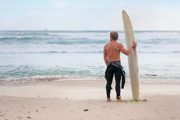 Uomo sulla spiaggia con la tavola da surf