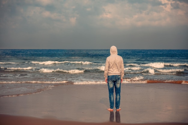 Uomo sulla spiaggia L'uomo in piedi a piedi nudi sulla spiaggia e guardando il mare