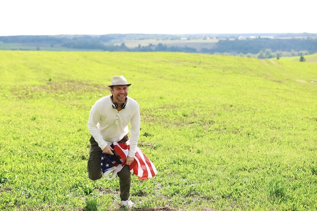 Uomo sventola bandiera americana in piedi in erba fattoria vacanze campo agricolo patriottismo orgoglio libertà partiti politici immigrato