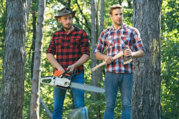 Uomo taglialegna tenendo ascia ascia nelle mani del boscaiolo taglio del legno Lumberman con una motosega nella foresta Concetto di una xilografia professionale di registrazione Lavoratori forestali