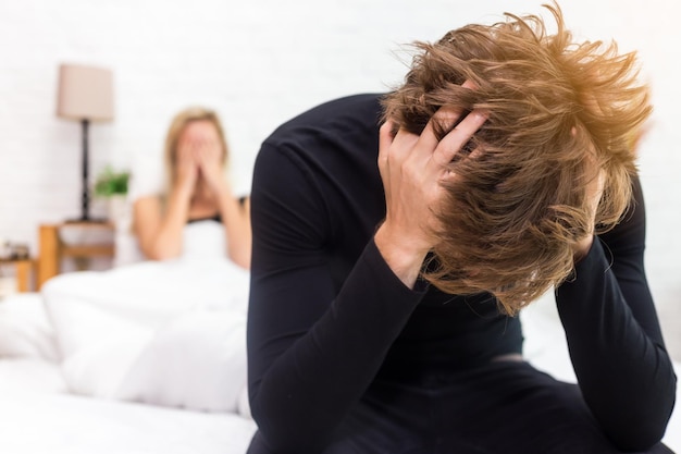Uomo teso con la fidanzata seduto a letto a casa