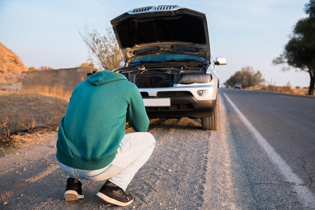 Uomo triste con l'auto rotta