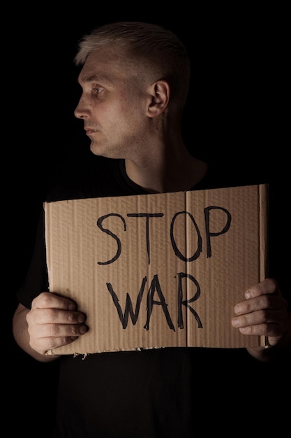 Uomo triste con poster Stop War su sfondo nero