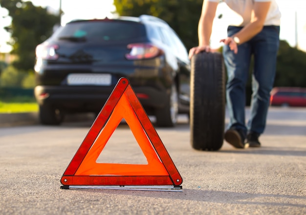 Uomo triste e depresso che si siede vicino all'automobile con la gomma perforata