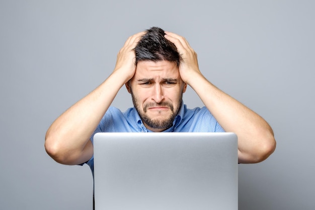 Uomo triste pensieroso che si siede al tavolo con il computer portatile