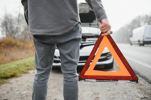 Uomo triste sulla strada accanto alla macchina rotta