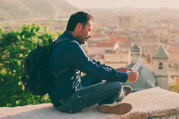 Uomo turistico bello che esamina mappa