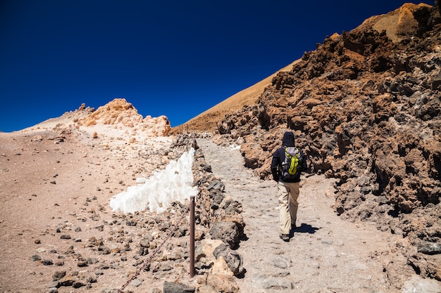 Uomo turistico con zaino andando alla sommità del vulcano Teide a Tenerife, Isole Canarie, Spagna