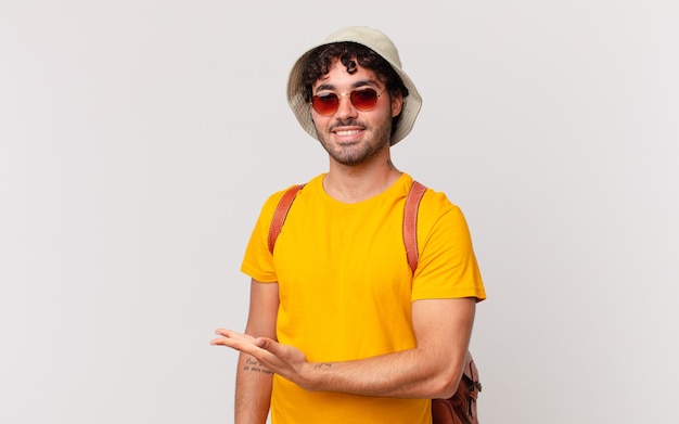 Uomo turistico ispanico che sorride allegramente, sentendosi felice e mostrando un concetto nello spazio della copia con il palmo della mano