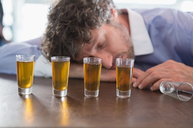 Uomo ubriaco che dorme su un bancone da bar