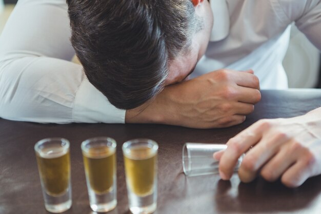 Uomo ubriaco che dorme su un bancone da bar