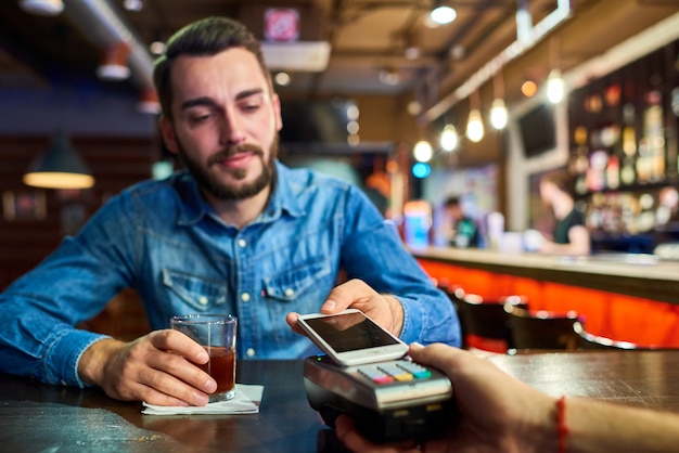 Uomo ubriaco che paga tramite NFC nella barra