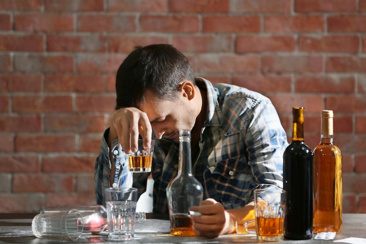 Foto uomo ubriaco seduto a tavola con alcol e droghe concetto di alcolismo