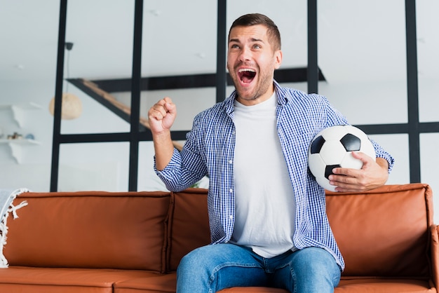 Uomo uscito con pallone da calcio sul divano