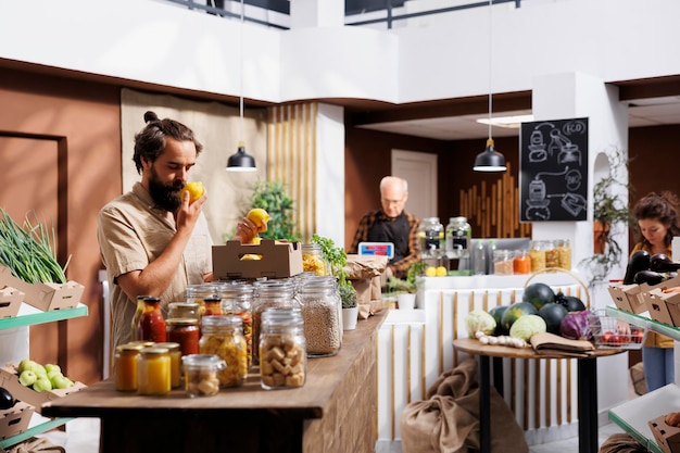 Uomo vegano che si gode il profumo fresco dei limoni coltivati in fattoria in un supermercato a rifiuti zero. Il cliente è felice di trovare frutta biologica ecologica nel negozio di quartiere locale rispettoso dell'ambiente