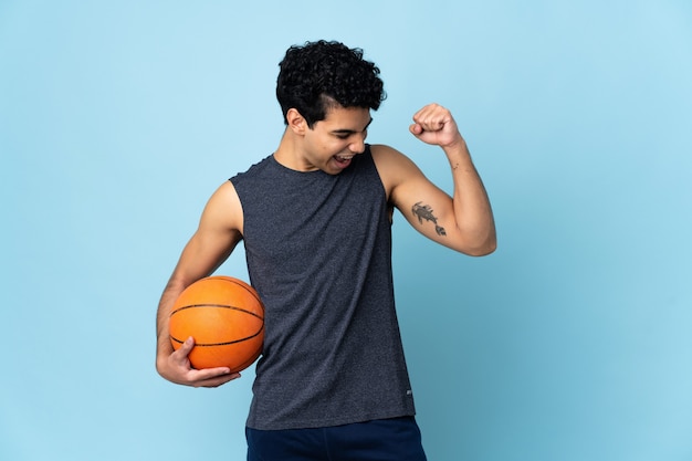 Uomo venezuelano del giocatore di pallacanestro sopra la parete isolata che celebra una vittoria