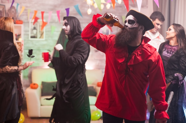 Uomo vestito come un pirata medievale che beve birra alla celebrazione di halloween.