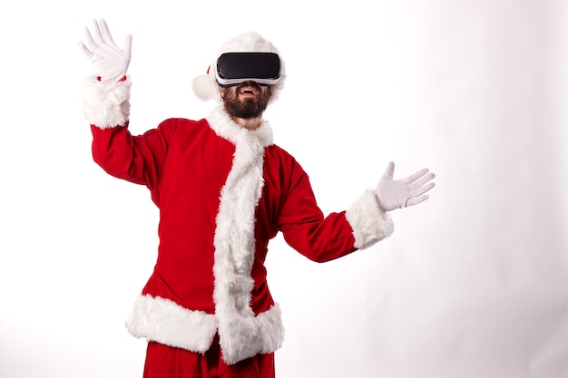 Uomo vestito da Babbo Natale con occhiali per realtà virtuale su sfondo bianco