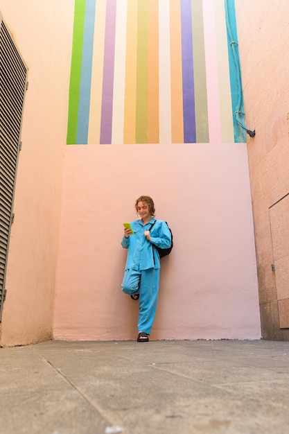 Uomo vestito di blu con un telefono su una parete rosa