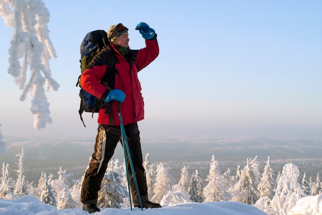 Uomo viaggiatore con uno zaino che guarda lontano da sotto il braccio in piedi sulla montagna