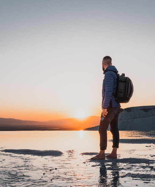 Uomo viaggiatore con zaino a Pamukkale che si gode il fantastico tramonto nei travertini