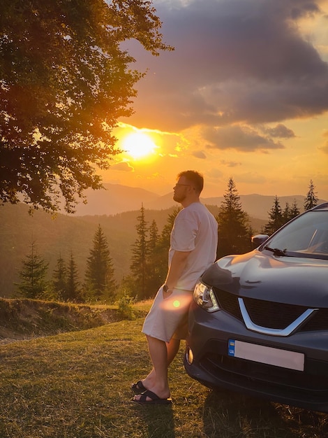 Uomo vicino auto Tramonto in montagna