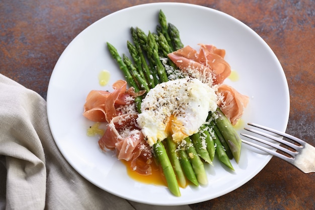 Uova alla Benedict con parmigiano, asparagi verdi e prosciutto di Parma.