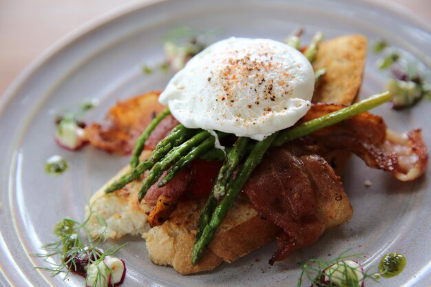 Uova alla benedict uovo in camicia su pancetta asparagi e pane colazione