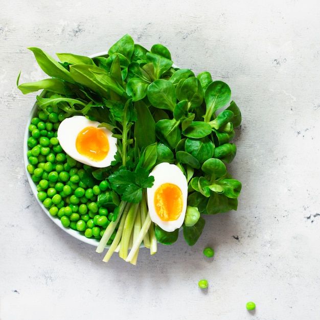 Uova alla coque con lattuga, aglio selvatico, piselli e prezzemolo. Concetto di mangiare sano. Diventa vegano