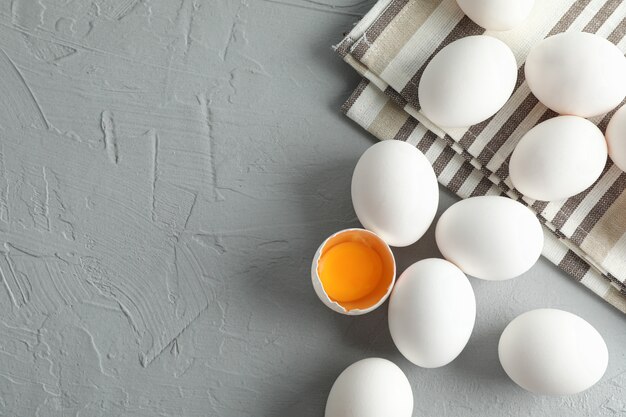 Uova bianche del pollo in asciugamano di cucina su gray