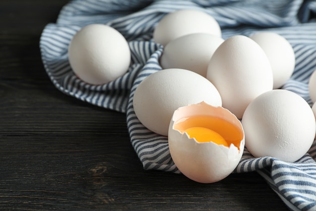 Uova bianche del pollo in contenitore di cartone ed asciugamano di cucina sulla tavola di legno