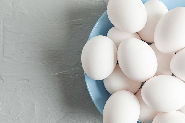 Uova bianche del pollo in zolla sulla tabella grigia