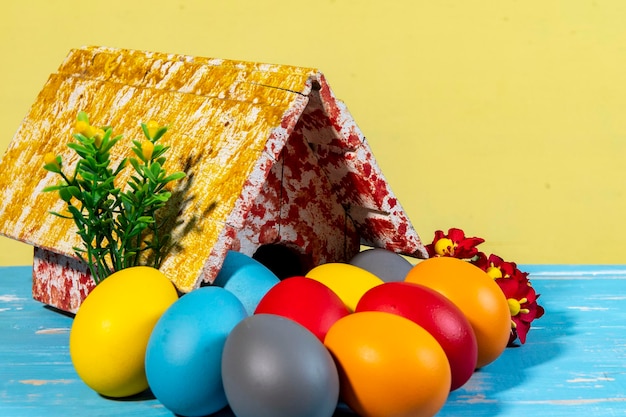 Uova colorate che simboleggiano la Pasqua con una casa giocattolo fiori come un giardino