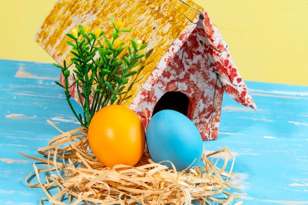 Uova colorate che simboleggiano la pasqua con una casa giocattolo fiorisce come un giardino