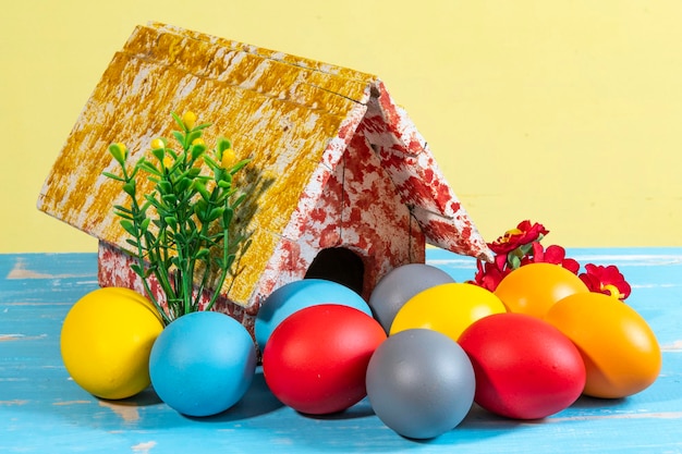 Uova colorate che simboleggiano la pasqua con una casa giocattolo fiorisce come un giardino