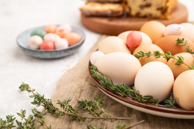 Uova colorate di pasqua fatte in casa e torta di uvetta su piatto su uno sfondo grigio cemento vista laterale primo piano fuoco selettivo