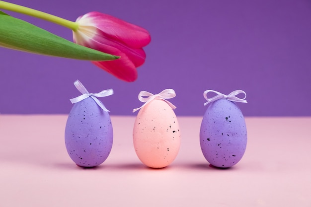 Uova con decorazioni e fiori su una superficie viola