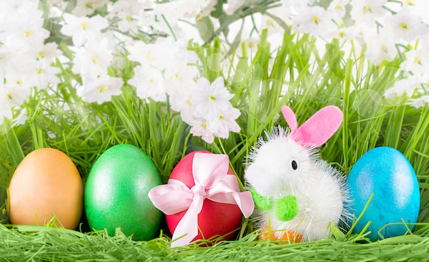 Uova decorate variopinte di Pasqua e Little Toy Bunny su erba verde