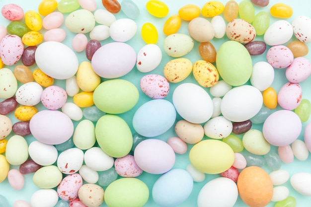 Uova di cioccolato della caramella di Pasqua e dolci di gelatina isolati sulla tavola blu