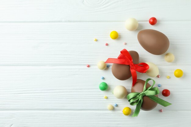 Uova di cioccolato di Pasqua e caramelle sulla tavola di legno bianca