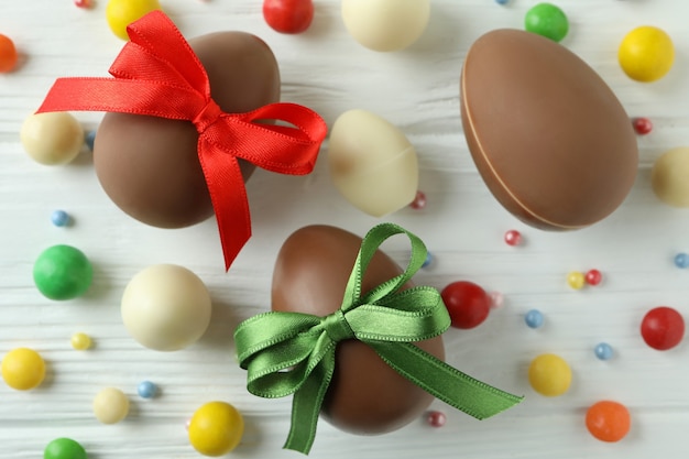 Uova di cioccolato di Pasqua e caramelle sulla tavola di legno bianca