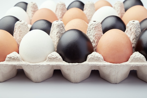 Uova di diversi colori in scatole di cartone. Uova di gallina nere, bianche e marroni.