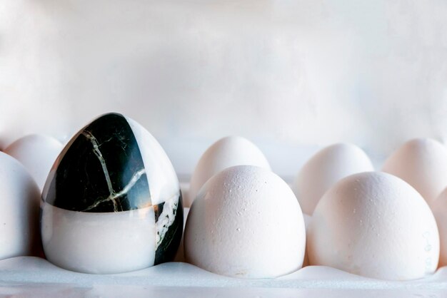 Uova di diversi colori in scatole di cartone uovo di pietra di marmo su uno sfondo di uova di gallina bianche