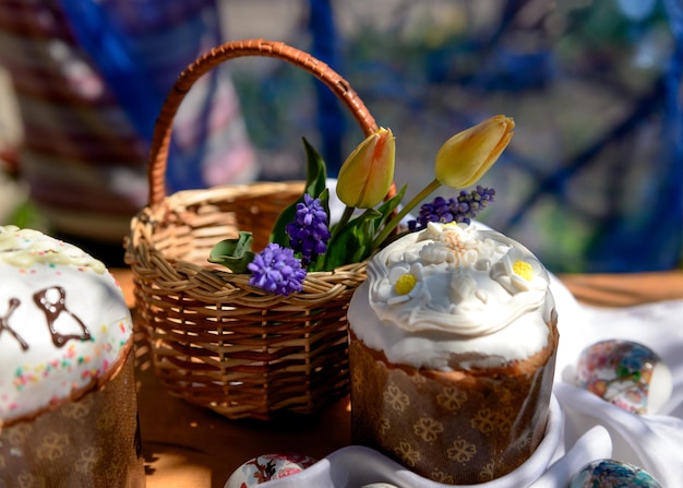 Uova di dolci pasquali e tulipani gialli e fiori viola in un cesto il giorno di Pasqua