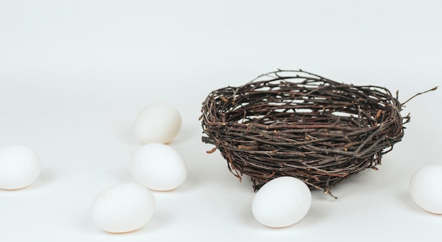Uova di gallina bianche giacciono intorno a un nido di rami. Sfondo di Pasqua con uova.