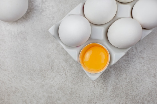 Uova di gallina bianche in supporto in ceramica su una superficie grigio chiaro